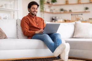 man casual orange shirt blue jeans sits comfortably white couch with his legs 116547 121160