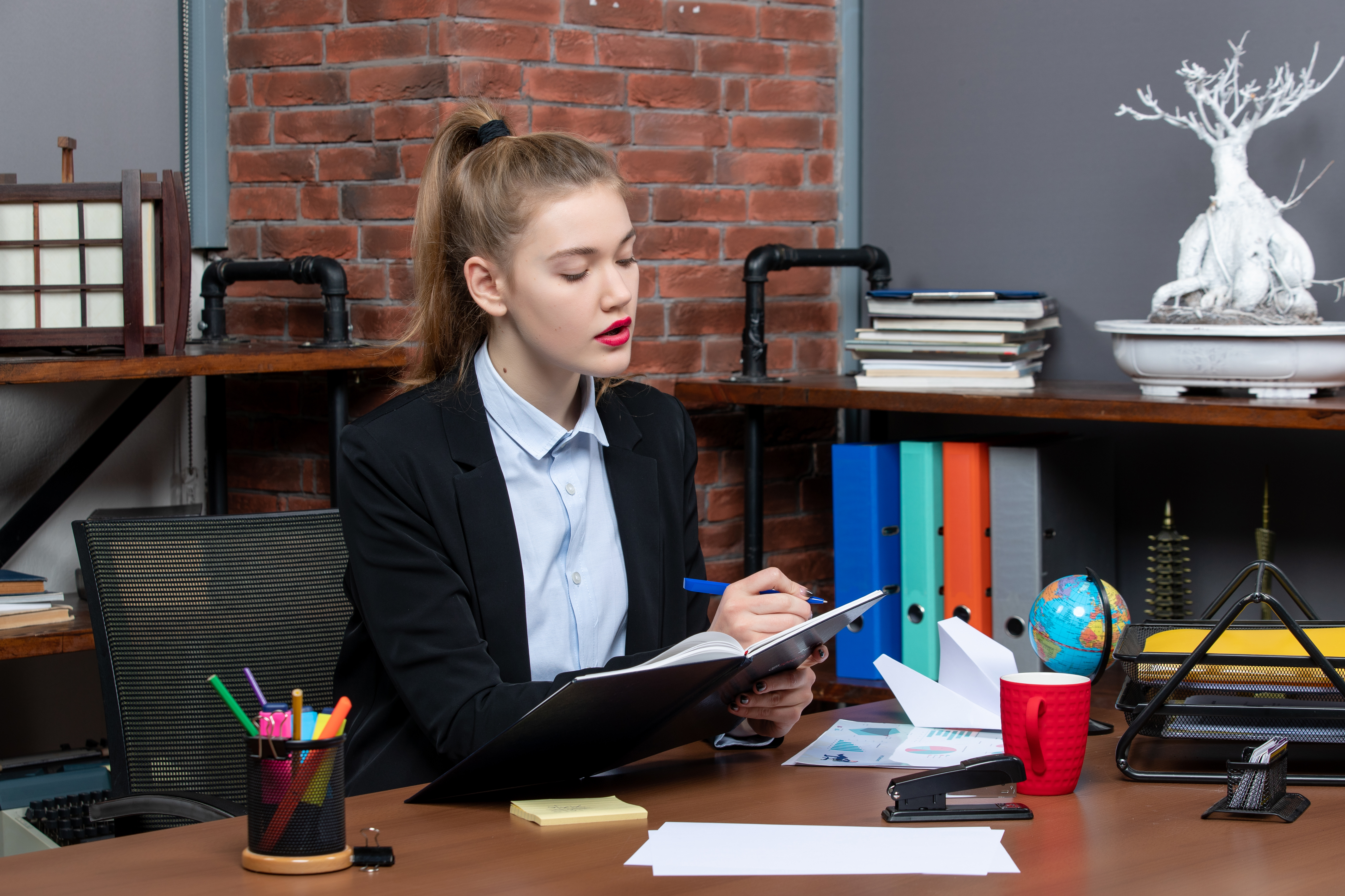 front view young confident female assistant sitting her desk writing her document office